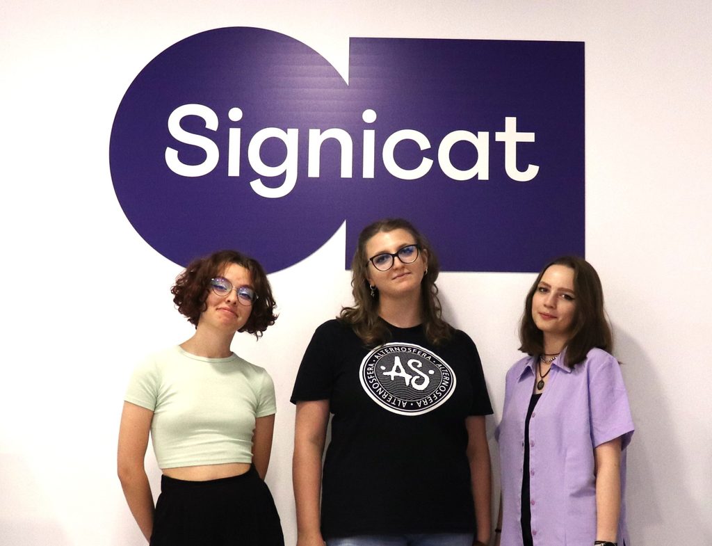 Three summer interns pictured under a Signicat sign